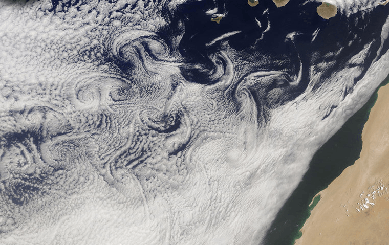 A cloud-filled sky, rugged islands, and turbulent air joined to create fanciful designs in the atmosphere